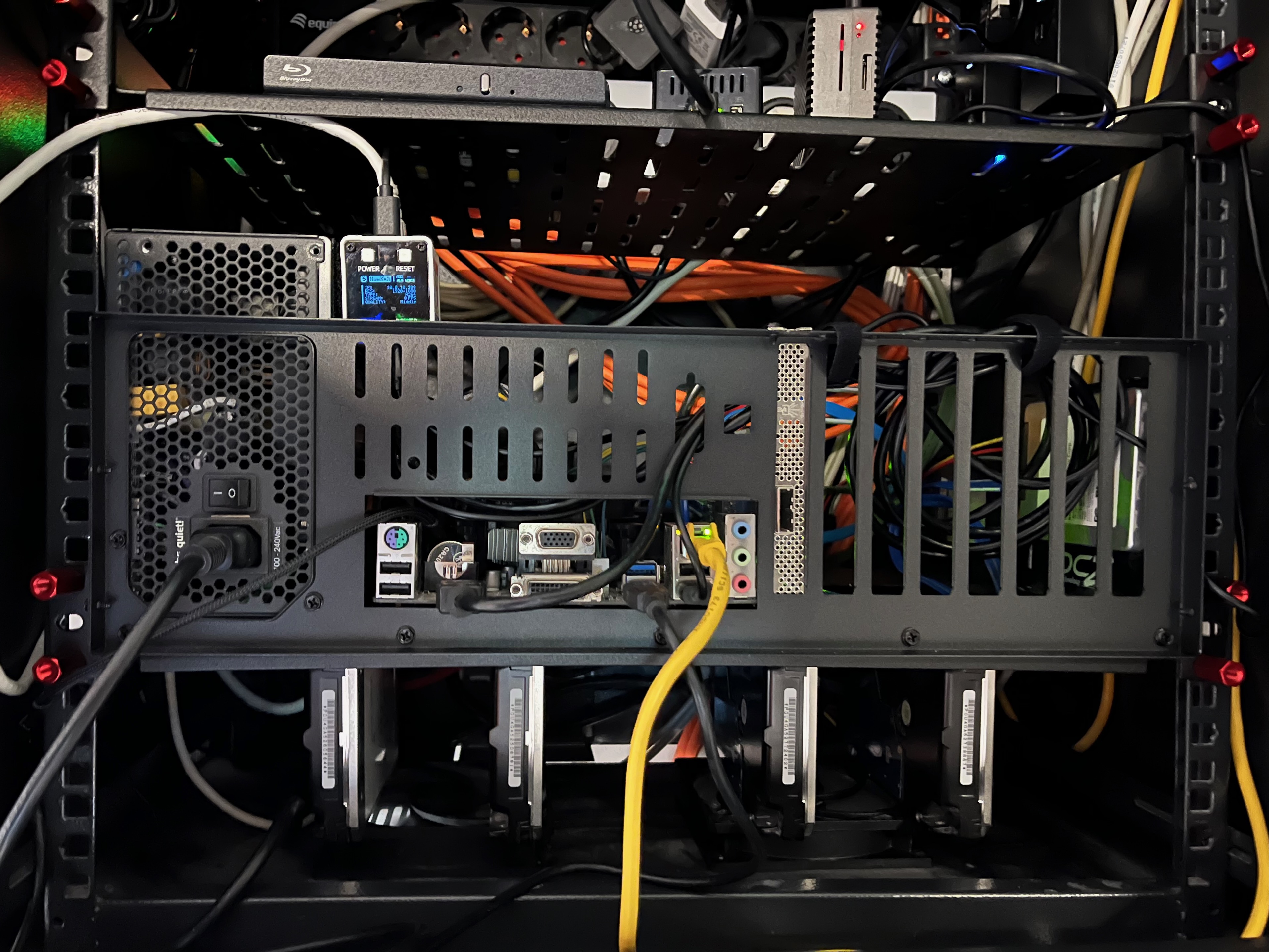 Rack-mounted homelab NAS with test bench motherboard holder and hard drives mounted beneath shelf using ventilation holes